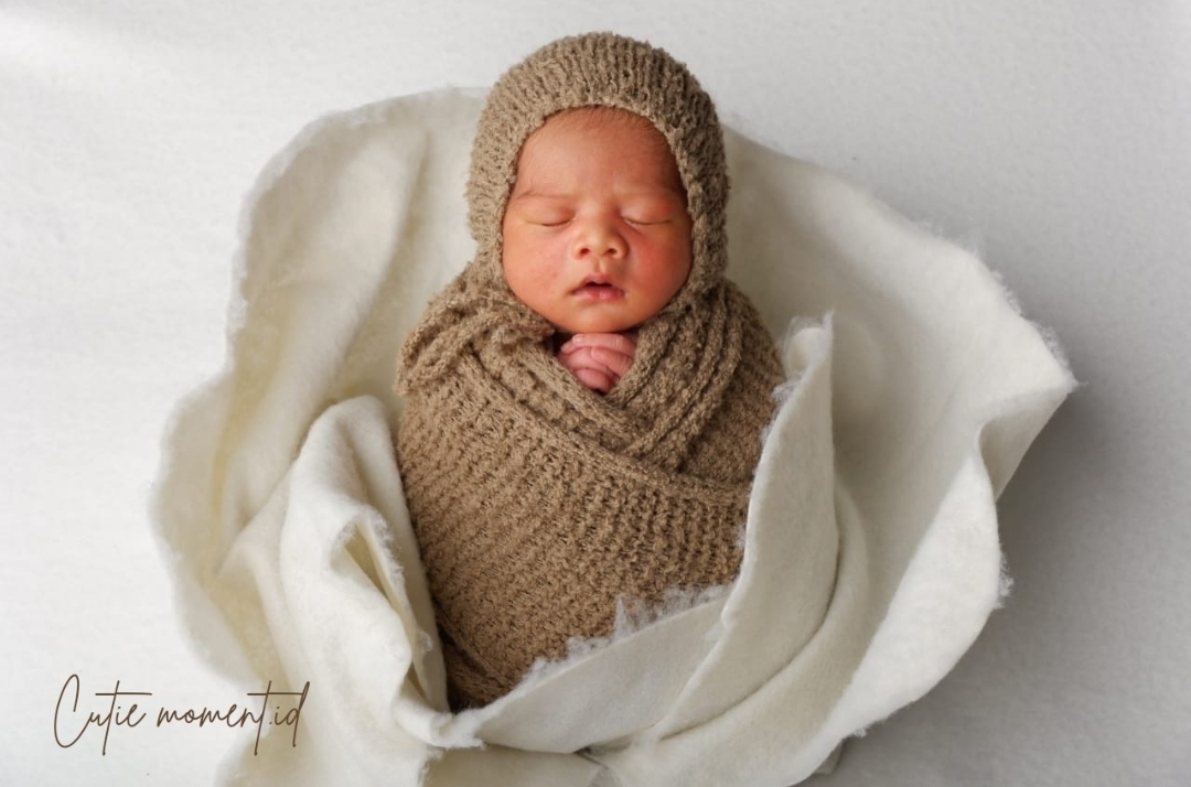 Foto bayi dibedong dengan kain rajut coklat